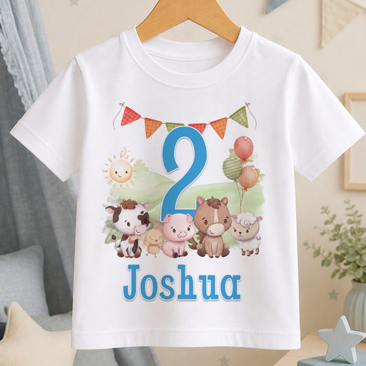 A white t-shirt with a cartoon image of farm animals and the number "2" printed on it, along with the name "Joshua" below.