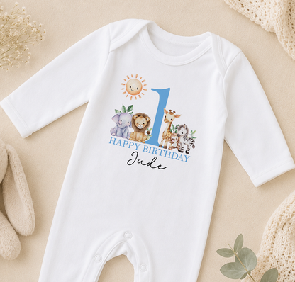Personalised white baby vest printed with a blue number 1, a lion, giraffe and elephant, and 'Happy Birthday Jude'.