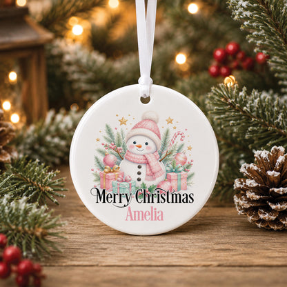 Personalised snowman Christmas bauble, white ceramic ornament with a pink snowman, presents and candy canes, printed with Merry Christmas and a name