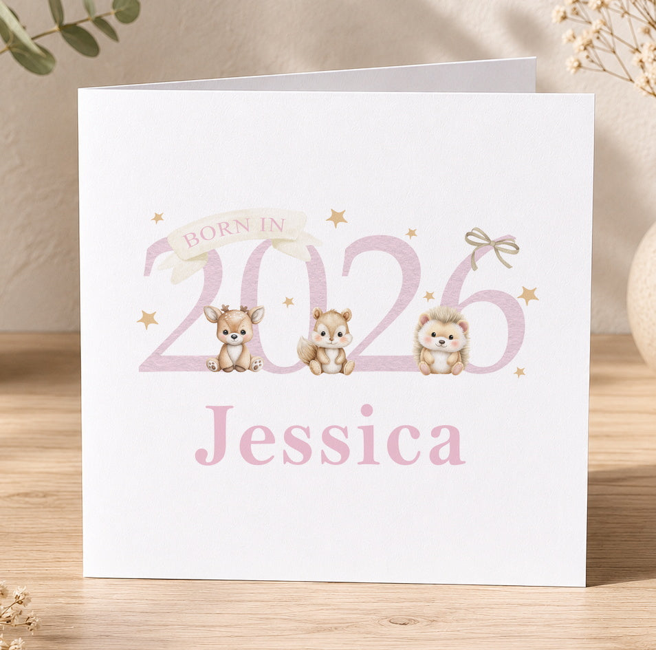 White square newborn card standing against a pink sparkly backdrop, reading 'Born In 2026' in pink lettering with an illustrated deer, chipmunk and hedgehog, personalised with the name Jessica