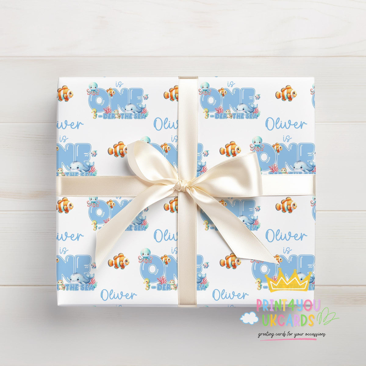 Gift box with a white ribbon wrapped in the personalised ocean wrapping paper, featuring a custom name and sea creature design