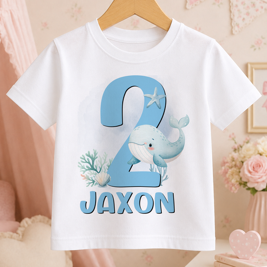 A white t-shirt with a blue whale and coral design, along with the text "JAXON" printed on it.