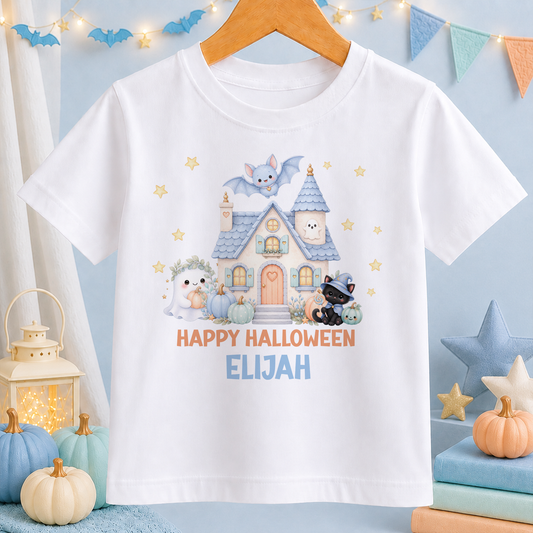A white t-shirt with a Halloween-themed graphic design, including a house, bats, and other spooky elements, along with the text "HAPPY HALLOWEEN ELIJAH".