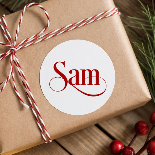 Personalised red script name sticker on a wrapped Christmas gift with rustic red and white twine