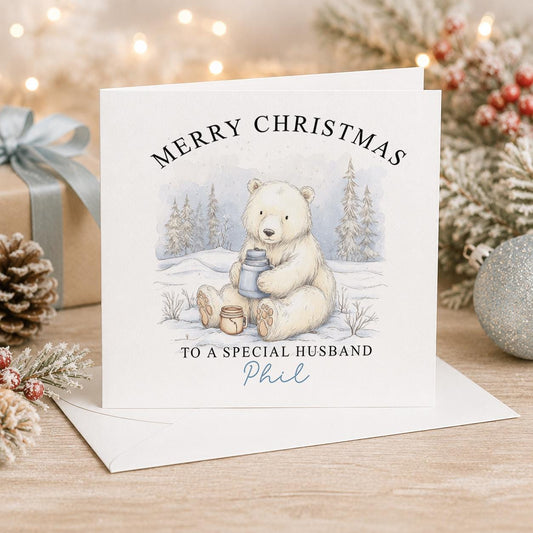 Personalised Christmas card, white 6x6 inch square card printed with a polar bear cub building a snowman with Merry Christmas and a name