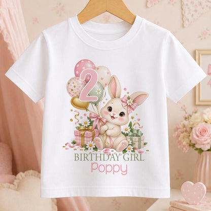 Personalised white t-shirt with a cream bunny in a pink gingham bow, balloons and daisies with an age number and Birthday Girl above a name
