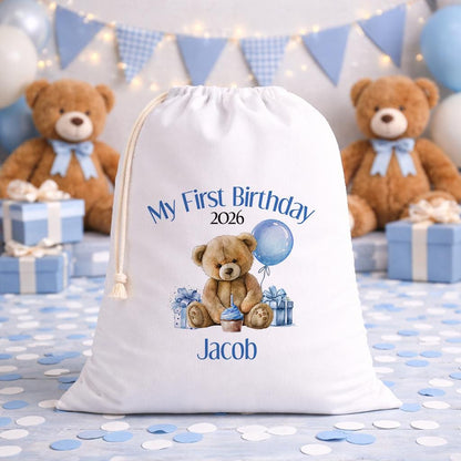 Personalised blue teddy first birthday sack laid flat, showing the printed name and teddy bear design