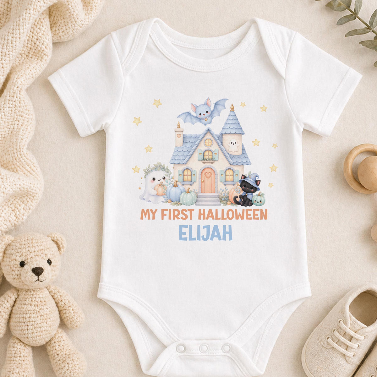 Personalised baby first Halloween vest printed with a pastel haunted house, ghost, black kitten wizard, bat and pumpkins, finished with the baby's name.