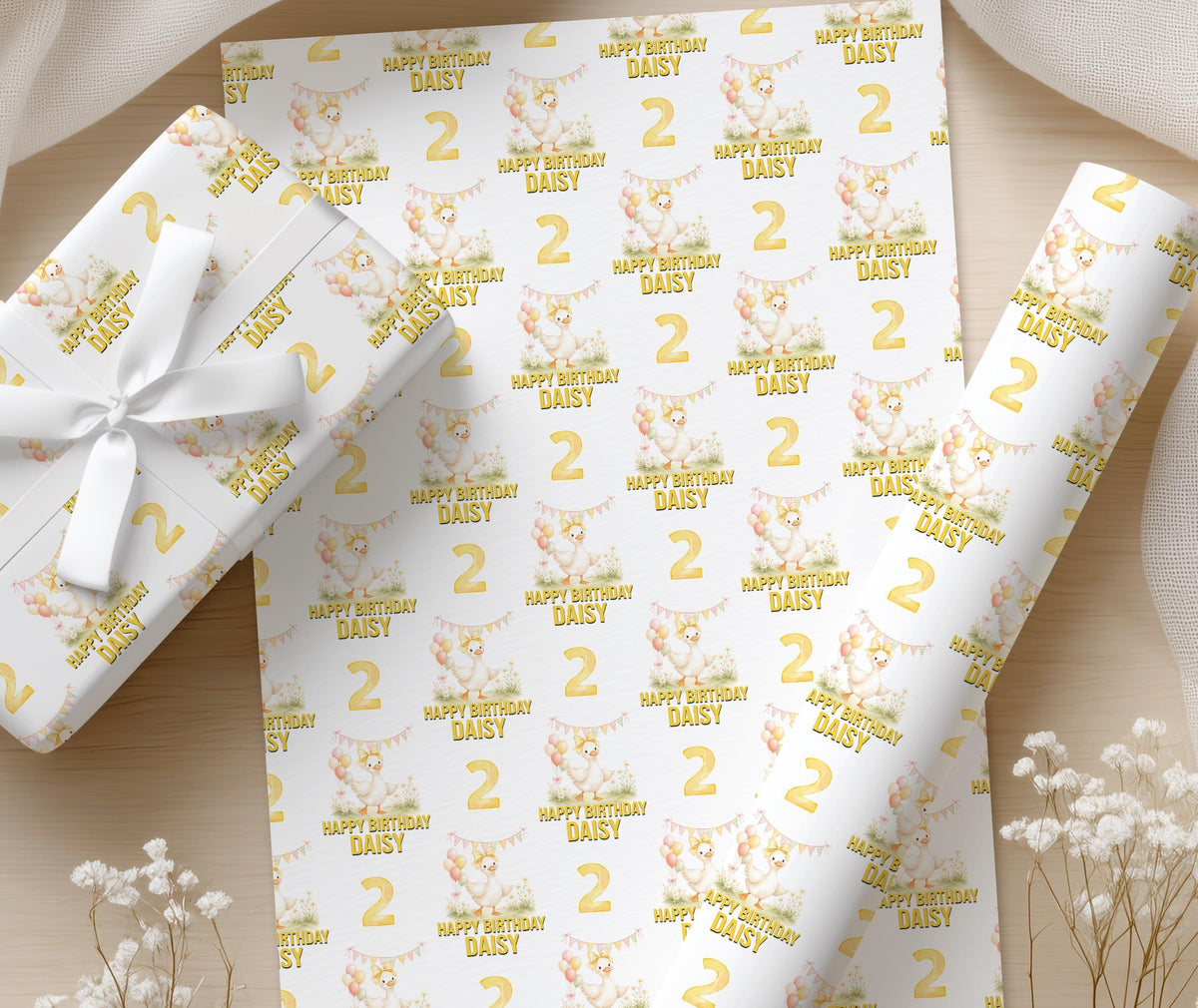 Close-up of the yellow duck and balloon design showing the custom name and age printed on the birthday wrapping paper.