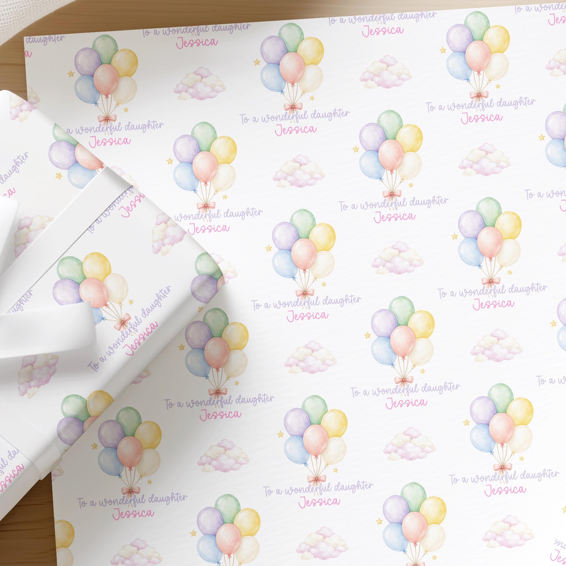 Close-up of the personalised pastel balloon and cloud wrapping paper with a custom name, birthday gift wrap for a daughter