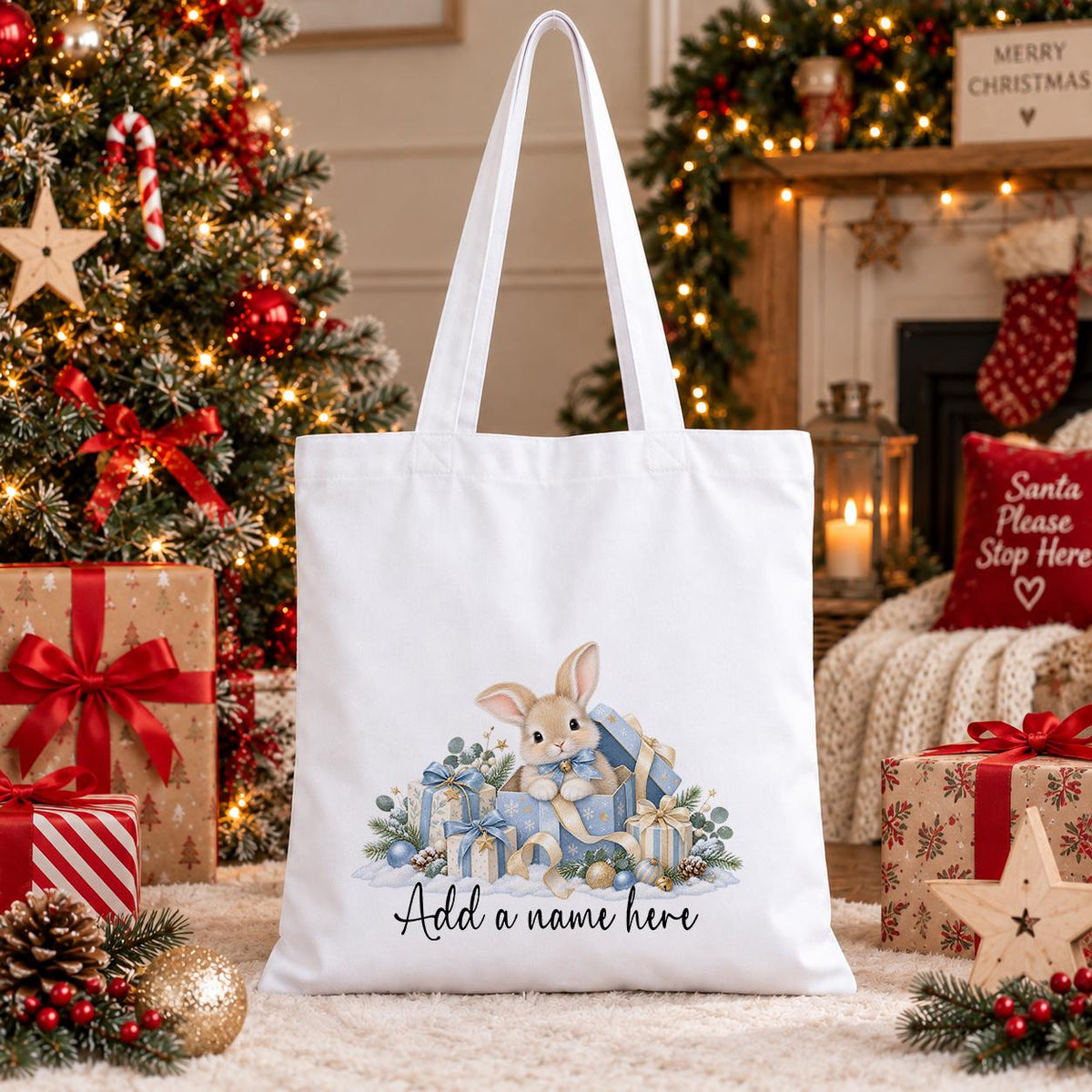 White cotton tote bag printed with a watercolour bunny rabbit sitting in a blue present with gold bows, above a name.