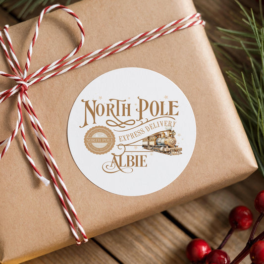 Gold vintage North Pole Express train Christmas sticker with a personalised name, round gift label tied onto a wrapped brown gift box