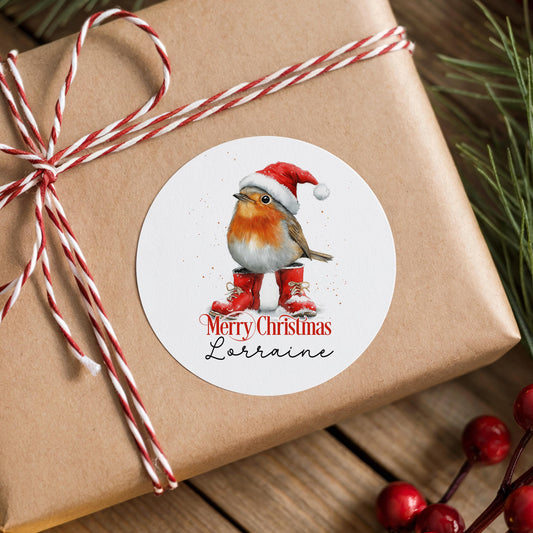 Personalised robin Christmas sticker in a Santa hat and red boots, stuck on a rustic gift box wrapped with twine and pine branches