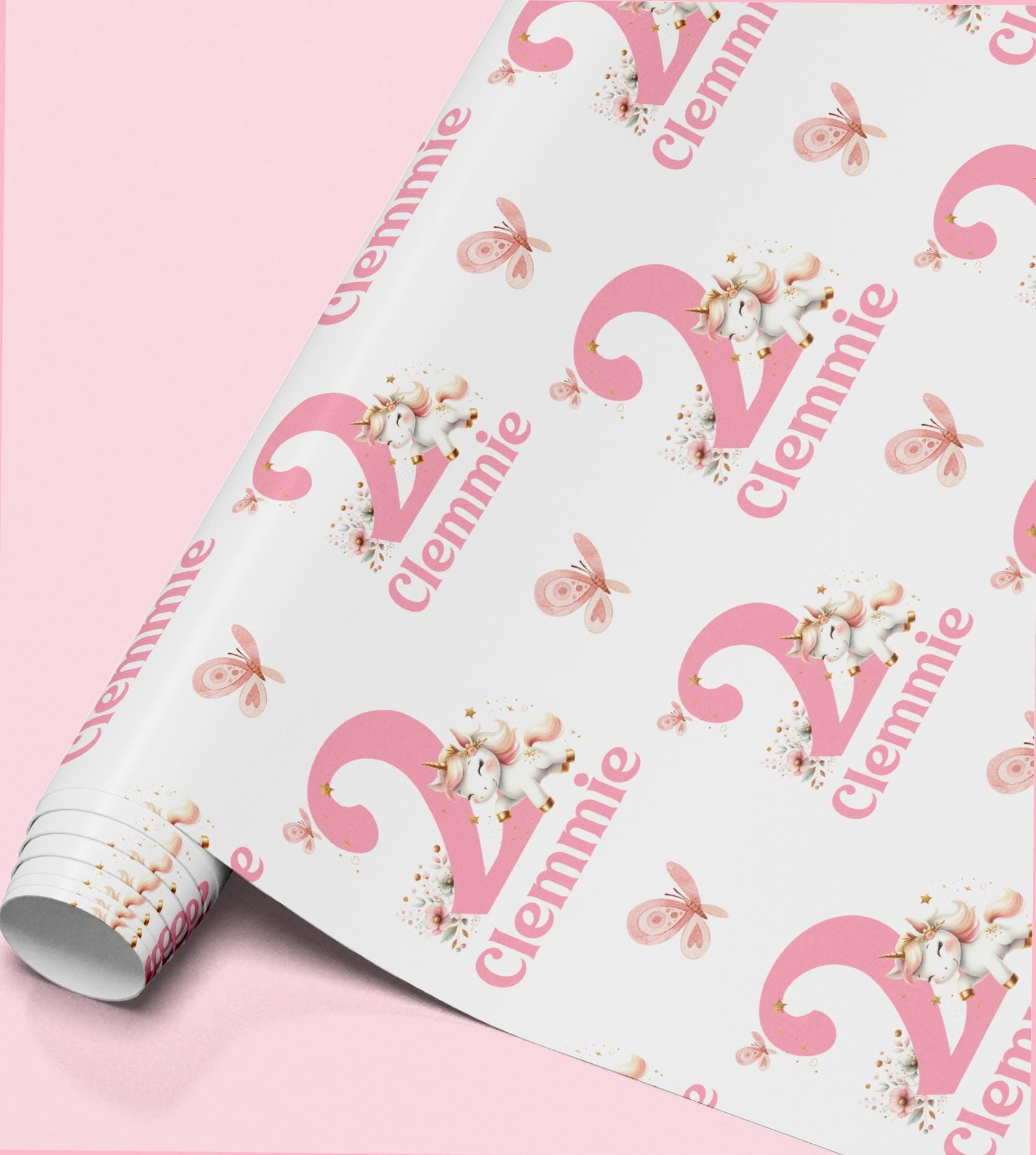 Pink and white unicorn wrapping paper personalised with the name 'Clennie', repeated across the pattern with butterflies