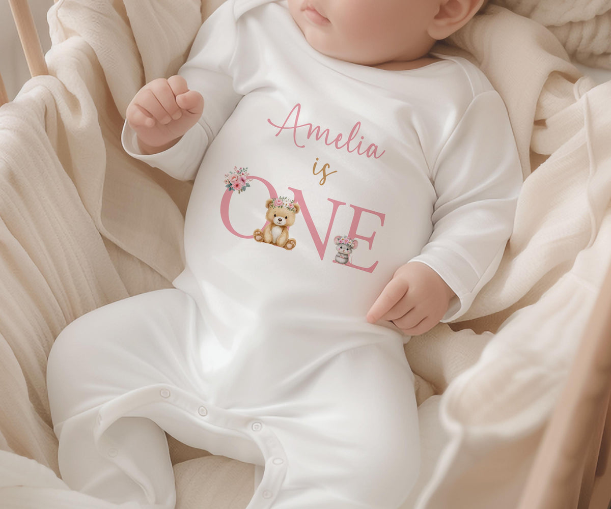 First birthday garment printed with a floral teddy bear design, laid flat to show the full print.