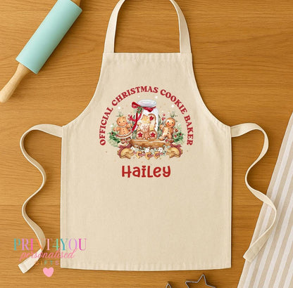 Personalised childrens Christmas apron shown flat, natural cotton drill with a gingerbread house design and a name