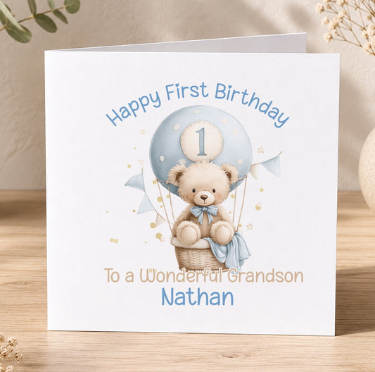 Square 1st birthday card featuring a teddy bear and hot air balloon design, personalised with the child's name for a son's first birthday.