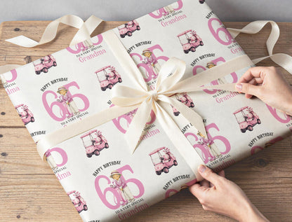 Personalised golf wrapping paper sheet laid flat showing the full repeating lady golfer and pink golf buggy pattern with age.