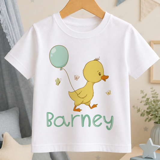 A white t-shirt with a cartoon duck and a green balloon, along with the name "Barney" printed on it.