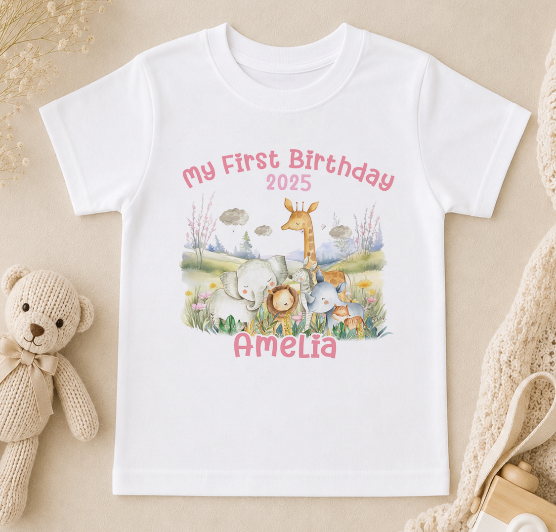 A white t-shirt with a personalized birthday message and an illustration of various animals, including a giraffe, elephants, and a teddy bear, along with the name "Amelia" and the year "2025".