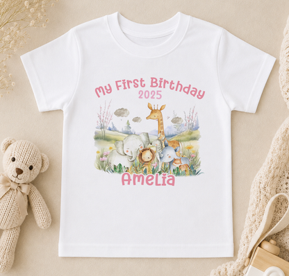 A white t-shirt with a personalized birthday message and an illustration of various animals, including a giraffe, elephants, and a teddy bear, along with the name "Amelia" and the year "2025".
