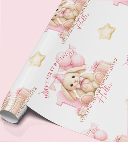Roll of personalised first birthday wrapping paper featuring a repeating bunny rabbit, pink number one and balloon design.