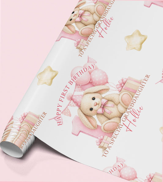 Roll of personalised first birthday wrapping paper featuring a repeating bunny rabbit, pink number one and balloon design.
