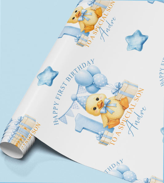 Roll of personalised first birthday wrapping paper featuring a repeating duckling, blue number one and balloon design.