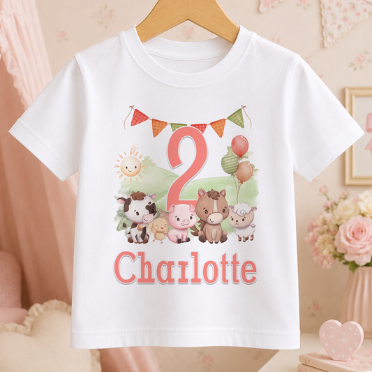 A white t-shirt with a personalized birthday design featuring a cow, pig, sheep, and horse, along with the name "Charlotte" and the number "2".