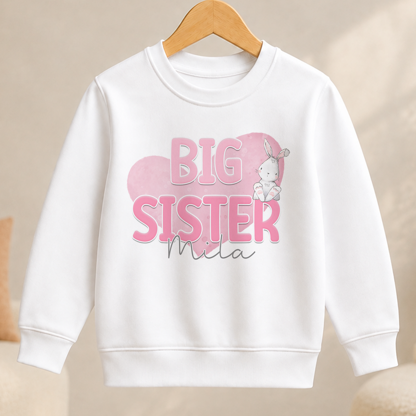 A white sweater with a pink and white design featuring the text "BIG SISTER" and a cartoon rabbit.