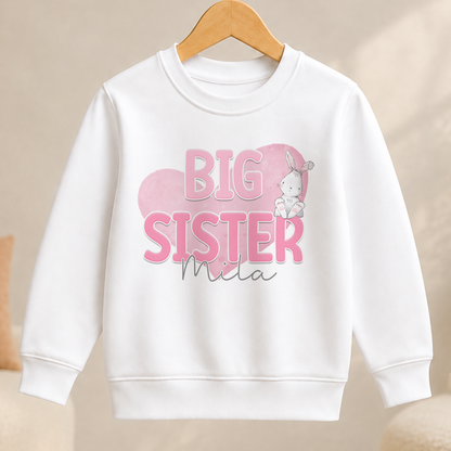 A white sweater with a pink and white design featuring the text "BIG SISTER" and a cartoon rabbit.