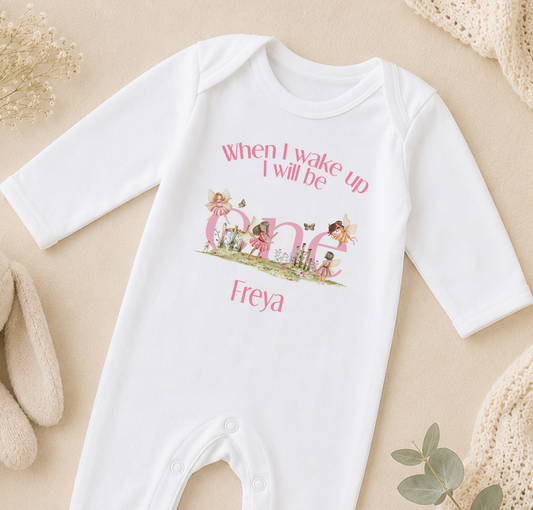 A white onesie with a personalized text and illustrations on it, placed on a beige surface.