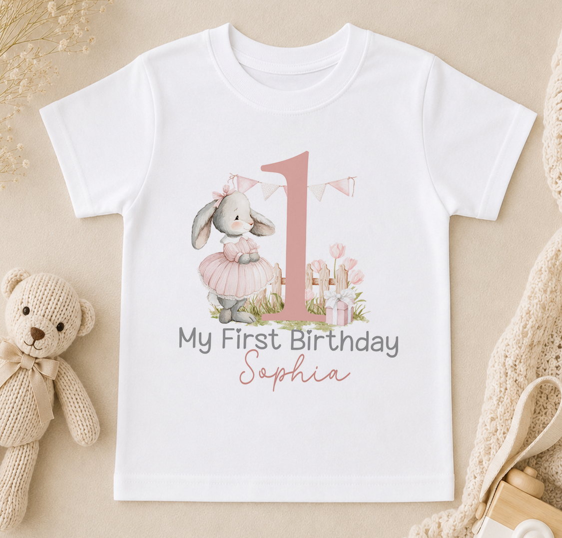 A white t-shirt with a pink number one and a pink bunny wearing a pink tutu, along with the text "My First Birthday Sophia".