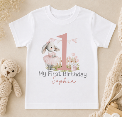 A white t-shirt with a pink number one and a pink bunny wearing a pink tutu, along with the text "My First Birthday Sophia".