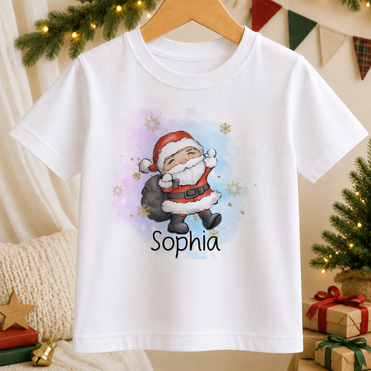 A white t-shirt with a colorful illustration of a smiling Santa Claus character and the name "Sophia" printed on it, hanging on a wooden hanger.