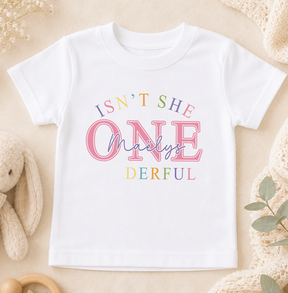 White T-shirt printed with the colourful phrase 'Isn't she ONE-derful' and the personalised name