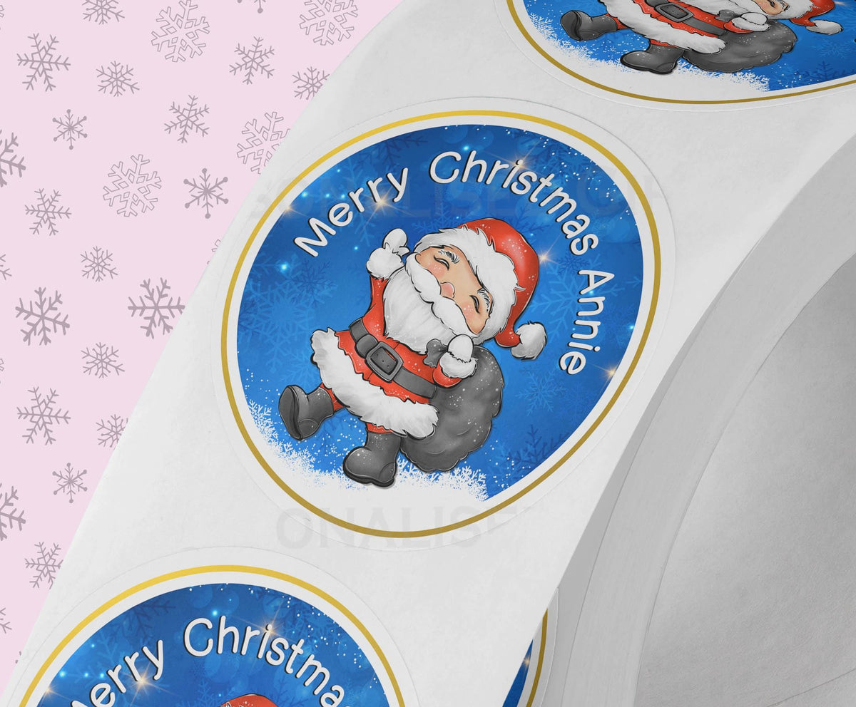 Glossy white round Christmas sticker personalised with a name, printed with a traditional Father Christmas design, shown on a strip of stickers