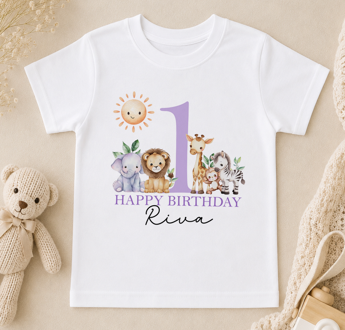 A white t-shirt with a graphic design featuring a sun, a giraffe, an elephant, and a lion, along with the text "Happy Birthday Riva".