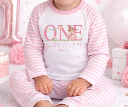 Personalised first birthday pyjamas with a pink fairy design and the baby's name printed on the front.