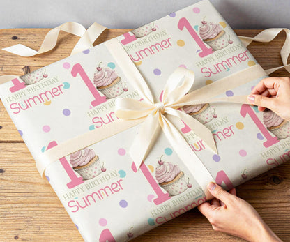 Personalised pink cupcake wrapping paper rolled and shown against a plain background