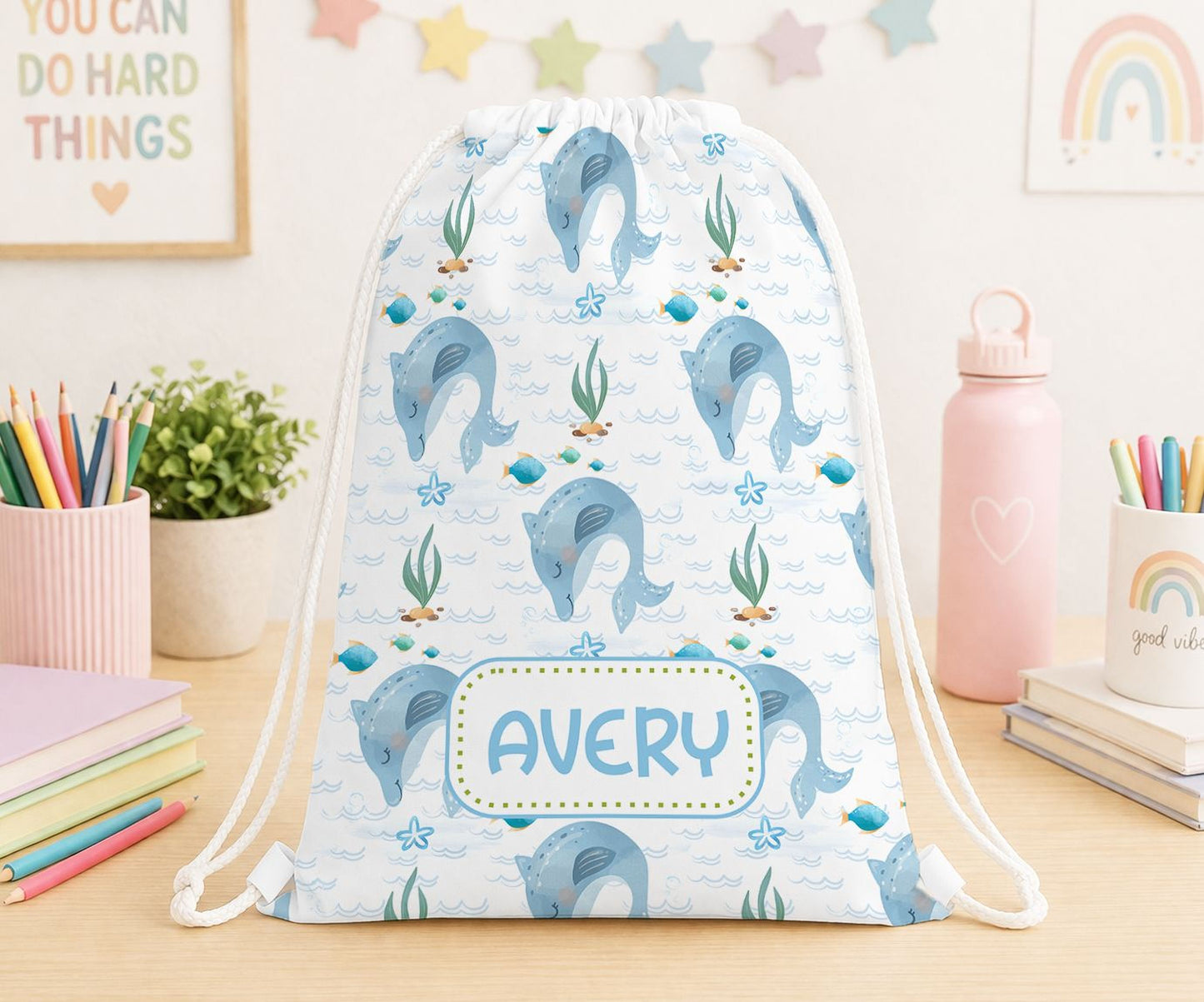 Personalised drawstring bag in white polyester printed with a cheerful dolphin design and a custom name, ideal for kids' swimming or PE kit