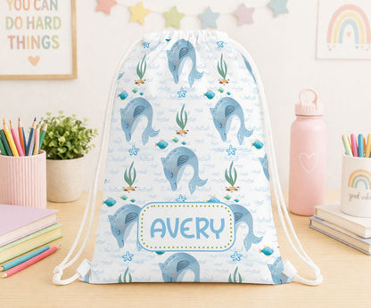 Personalised drawstring bag in white polyester printed with a cheerful dolphin design and a custom name, ideal for kids' swimming or PE kit