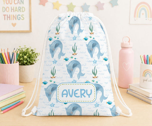 Personalised drawstring bag in white polyester printed with a cheerful dolphin design and a custom name, ideal for kids' swimming or PE kit