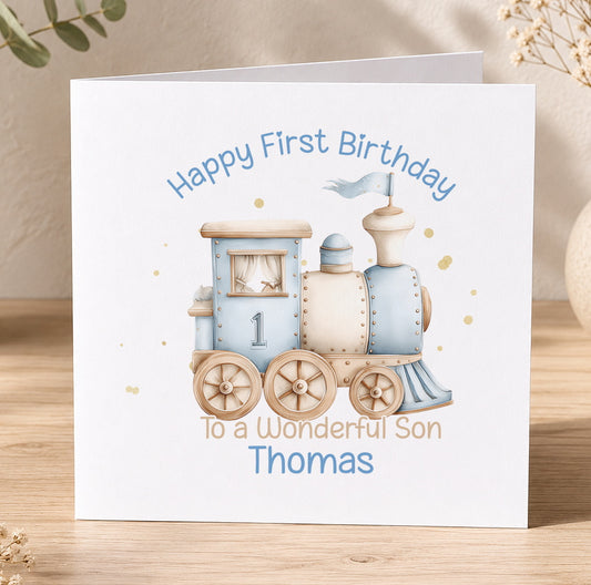 A white greeting card with a blue train illustration and text that reads "Happy First Birthday To a Wonderful Son Thomas".