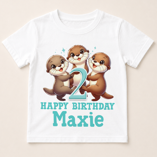A white t-shirt with a cartoon image of three otters and the number "2" on it, along with the text "Happy Birthday Maxie".