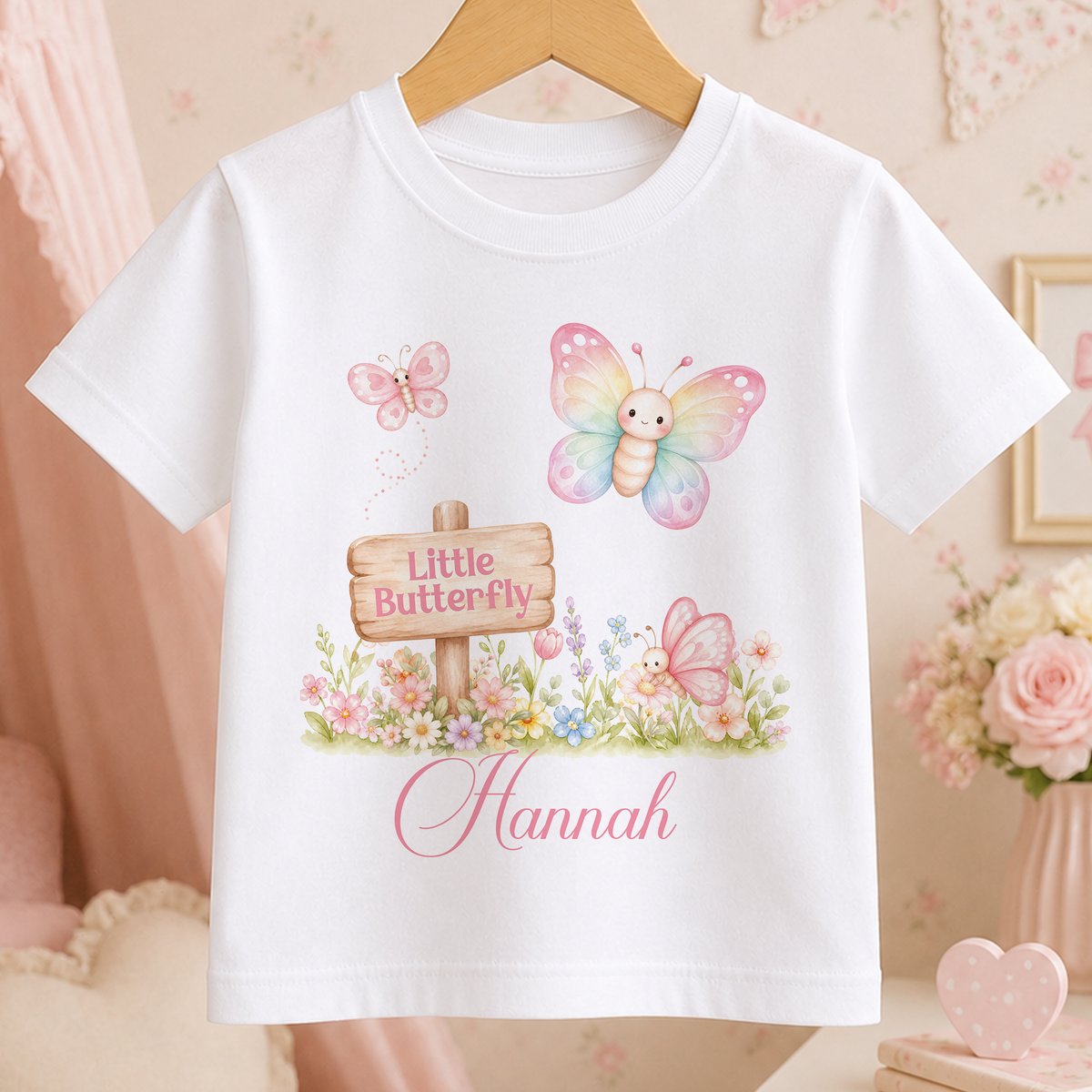 A white t-shirt with a design featuring a wooden sign, butterflies, and flowers.