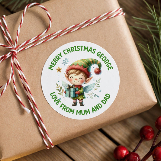 A brown gift box with a white label featuring a smiling elf holding a gift, surrounded by Christmas decorations and berries.
