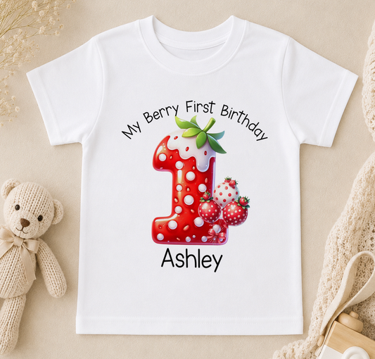 A white t-shirt with a red number one and strawberries printed on it, along with the text "My Berry First Birthday Ashley".