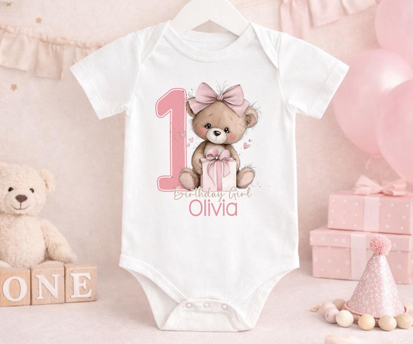 Close-up of the pink teddy bear design and personalised name on the first birthday outfit.
