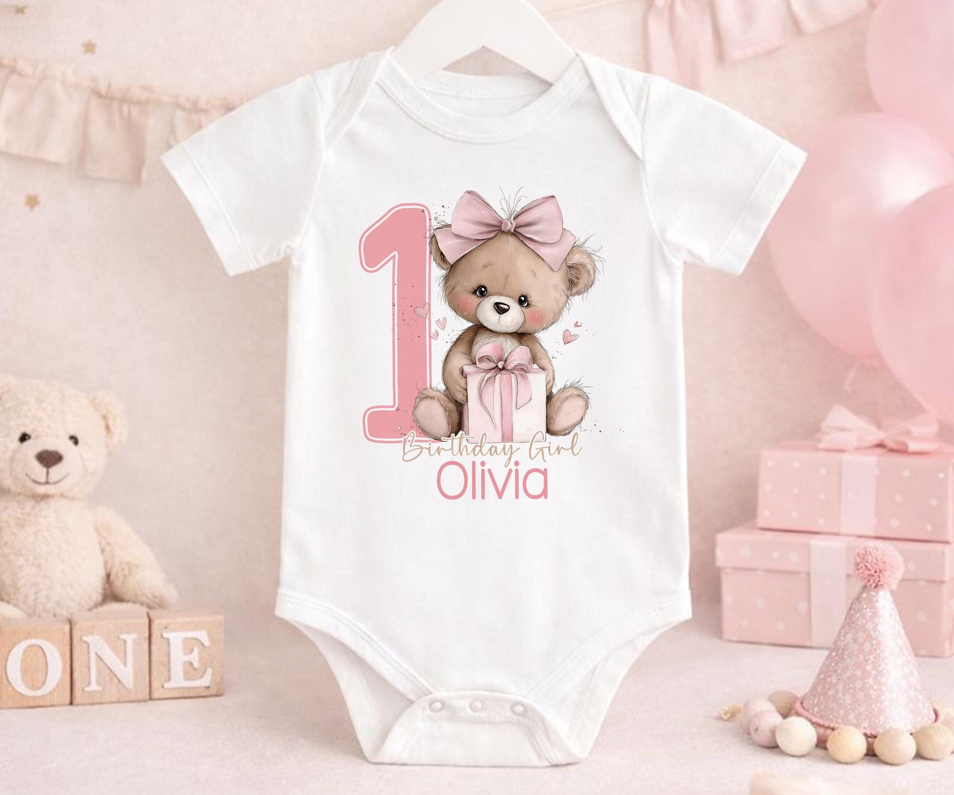 Close-up of the pink teddy bear design and personalised name on the first birthday outfit.
